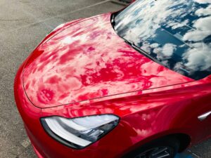 The front end of a glossy red Tesla with ceramic coating just applied to it.