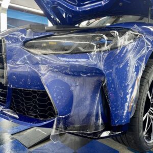 A blue car with PPF applied to the front bumper and headlights