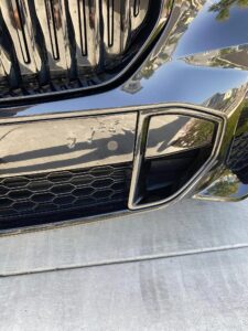 PPF peeling from the front bumper beside a grill